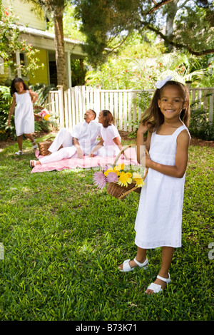 Happy African-American girl holding flower basket, family in background Stock Photo