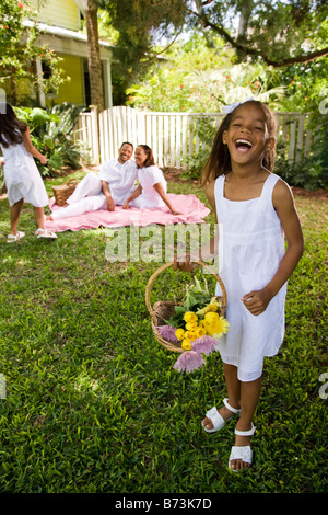 Happy African-American girl holding flower basket, family in background Stock Photo