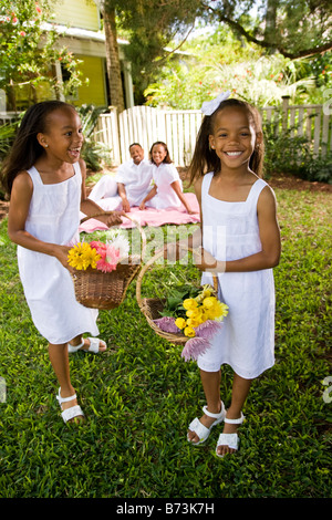 Happy African-American girls holding flower baskets, parents in background Stock Photo
