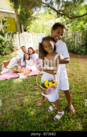 Happy African-American kids hugging, family in background on picnic blanket Stock Photo