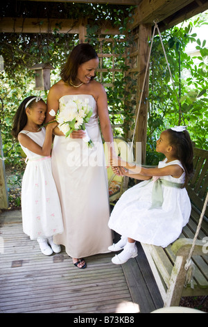 Happy African-American bride with flower girls in gazebo on wedding day Stock Photo