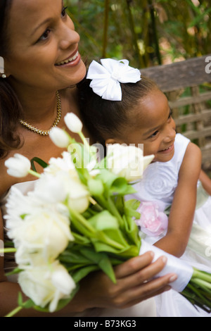 Closeup of happy African-American bride holding bouquet with flower girl Stock Photo