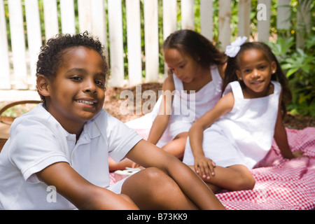 African-American children sitting on picnic blanket, boy in focus Stock Photo