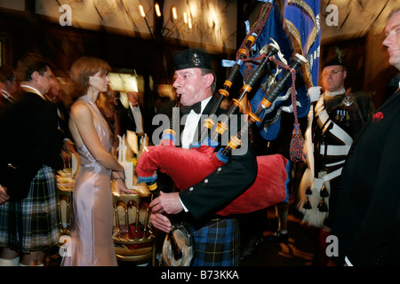 A piper leads in the guests at a traditional Burns Night supper Stock Photo