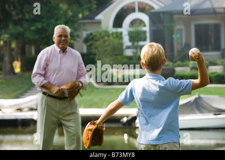 Grandfather and son playing baseball in back yard Stock Photo