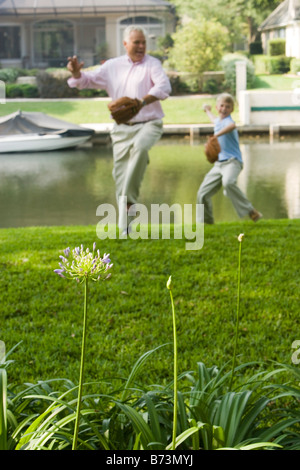 Grandfather and son playing baseball in back yard Stock Photo