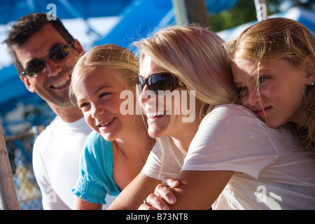 Portrait of family smiling while sitting at water park by wooden table Stock Photo