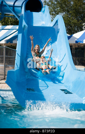 Mother and daughter sliding on water slide in water park Stock Photo