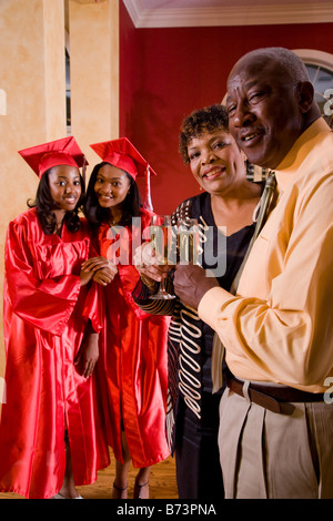 Young girls in graduation gown celebrating with grandparents Stock Photo