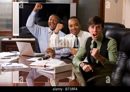 Excited multi-racial businessmen working in boardroom pumping fists Stock Photo
