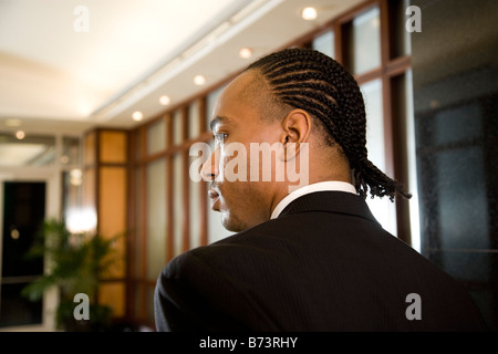 Rear view of young African-American businessman standing in lobby of office building Stock Photo