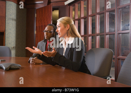 Two multi-racial businesspeople discussing in boardroom around table Stock Photo