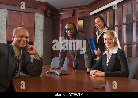 Four multi-racial businesspeople sitting in boardroom around table Stock Photo