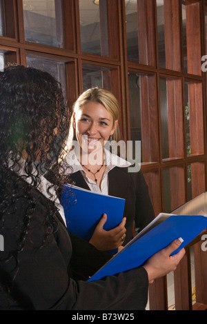 Two multi-racial businesswomen discussing reports in boardroom Stock Photo