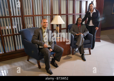 Three multi ethnic businesspeople sitting in office waiting room Stock Photo