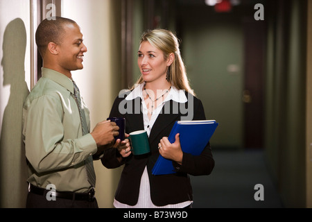 Two multi-racial office workers chatting in hallway Stock Photo