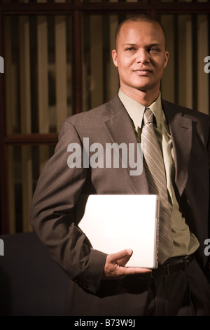 Young African-American businessman holding laptop in office Stock Photo