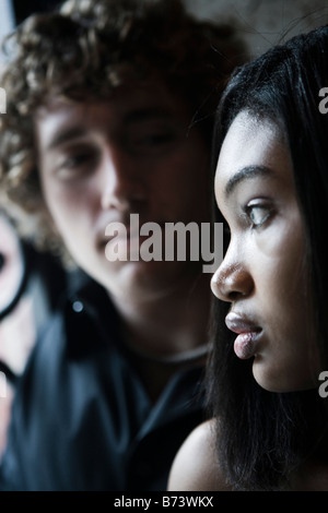 Close-up profile of young woman with young man in background Stock Photo