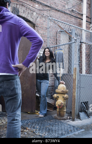 Young couple hanging out in back alley of old brick building Stock Photo