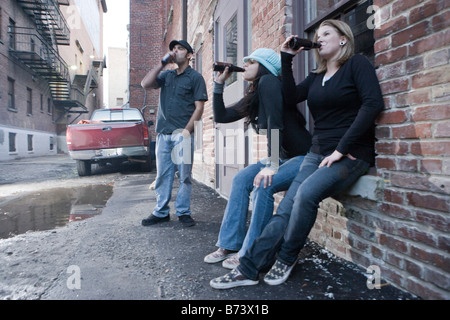 Urban youth hanging out in alleyway drinking beers and having fun Stock Photo