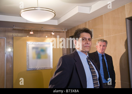Two multi-racial businessmen waiting for elevators in office Stock Photo