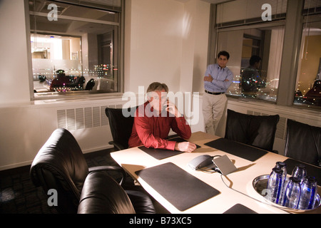 Two multi-racial businessmen in boardroom at night working late Stock Photo