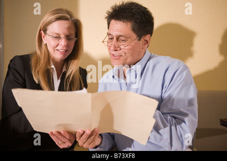 Two multi-racial businesspeople discussing reports in folder Stock Photo