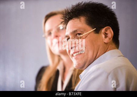 Close-up of middle-aged Hispanic businessman, woman in background Stock Photo