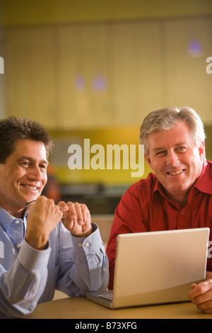 Two multi-racial businessmen working in office with laptop Stock Photo