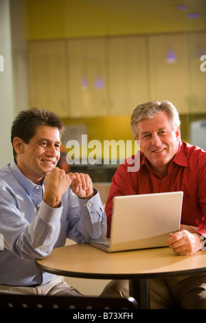 Two multi-racial businessmen working in office with laptop Stock Photo