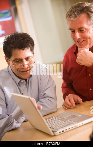 Two multi-racial businessmen having discussion on laptop in office Stock Photo