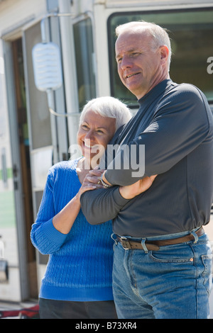 Senior couple standing together in front of recreational vehicle, smiling Stock Photo