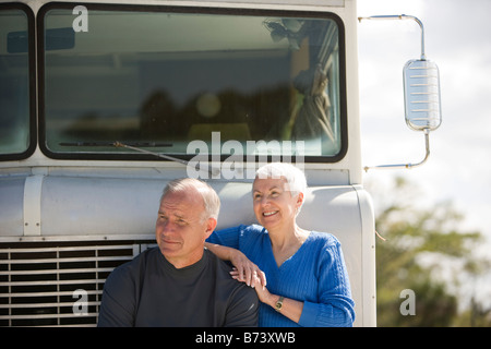 Senior couple leaning on recreational vehicle, smiling Stock Photo