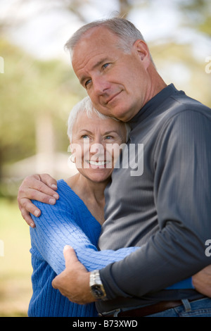 Senior couple hugging outdoors, smiling, side view Stock Photo