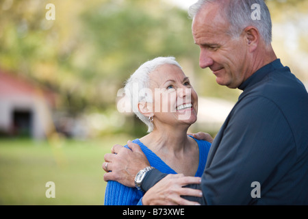 Side view of senior couple embracing outdoors, smiling Stock Photo