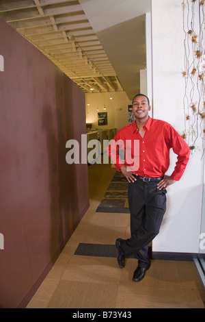 Young man leaning against wall in office corridor Stock Photo