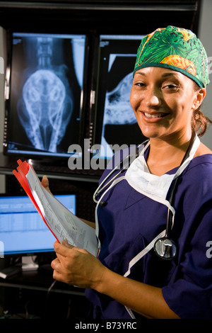 Veterinarian holding medical chart with animal x-rays in background Stock Photo