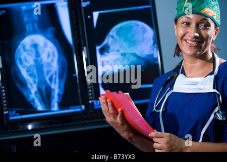 Veterinarian holding medical chart with animal x-rays in background Stock Photo