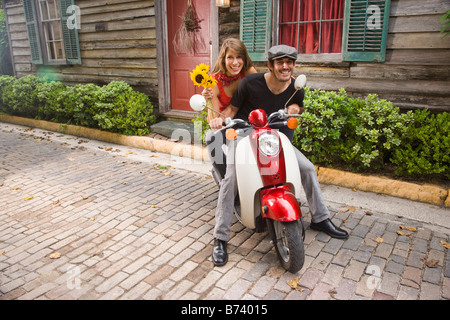 Young romantic couple on scooter on cobblestone road Stock Photo