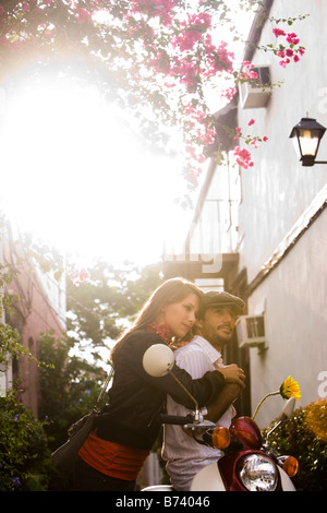 Young couple standing by motor scooter with building in background Stock Photo