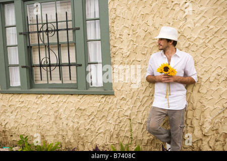 Young man holding flower standing outside alone Stock Photo