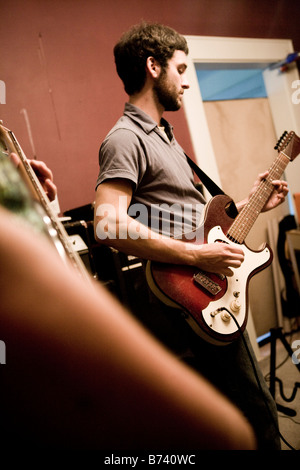 Young man playing guitar with band Stock Photo