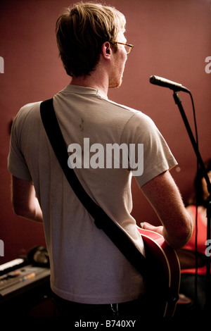 Young man playing guitar and singing into microphone Stock Photo
