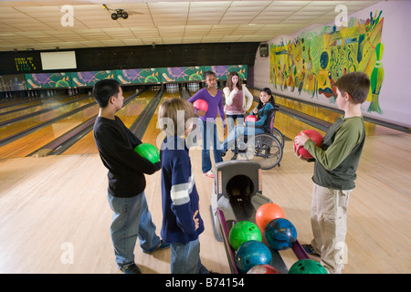Group of multi-racial friends with girl in wheelchair at bowling alley Stock Photo