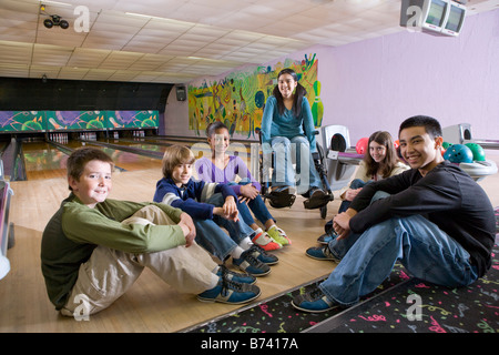 Group of multiracial children with girl in wheelchair in bowling alley Stock Photo