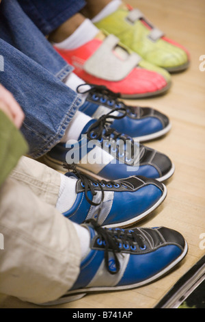 Three pairs of children's feet wearing bowling shoes Stock Photo