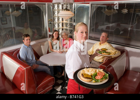 Waitress serving diners burgers and fries in casual restaurant Stock Photo