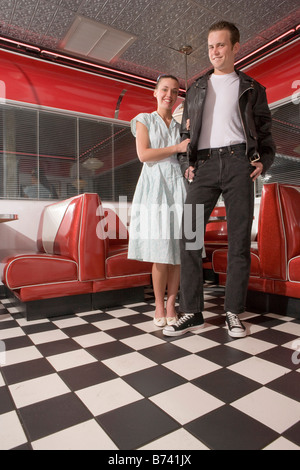 Portrait of young couple standing in diner wearing 1950s style clothing Stock Photo