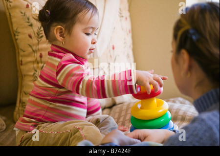 Hispanic mother watching daughter stack plastic rings Stock Photo