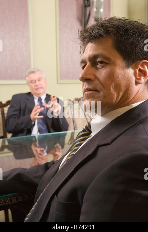 Two Multi-ethnic businessmen sitting in boardroom Stock Photo